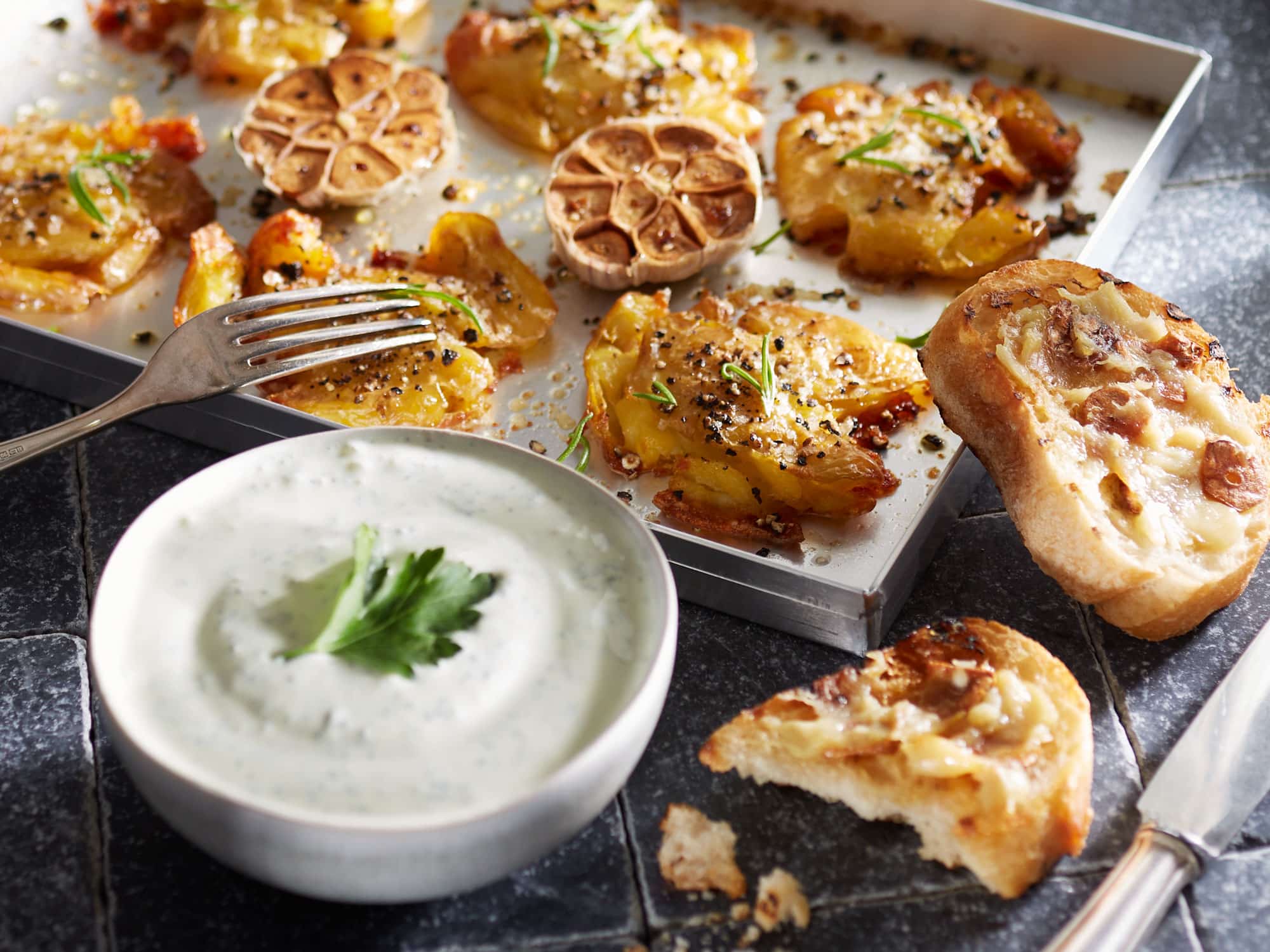 Smashed Potatoes mit Knoblauchbaguette, Petersilien-Dip und Rosmarin.