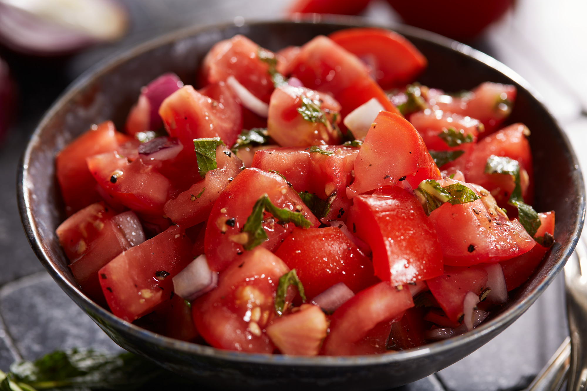 Frischer Tomatensalat mit Minze und Schalotten in Nahaufnahme.
