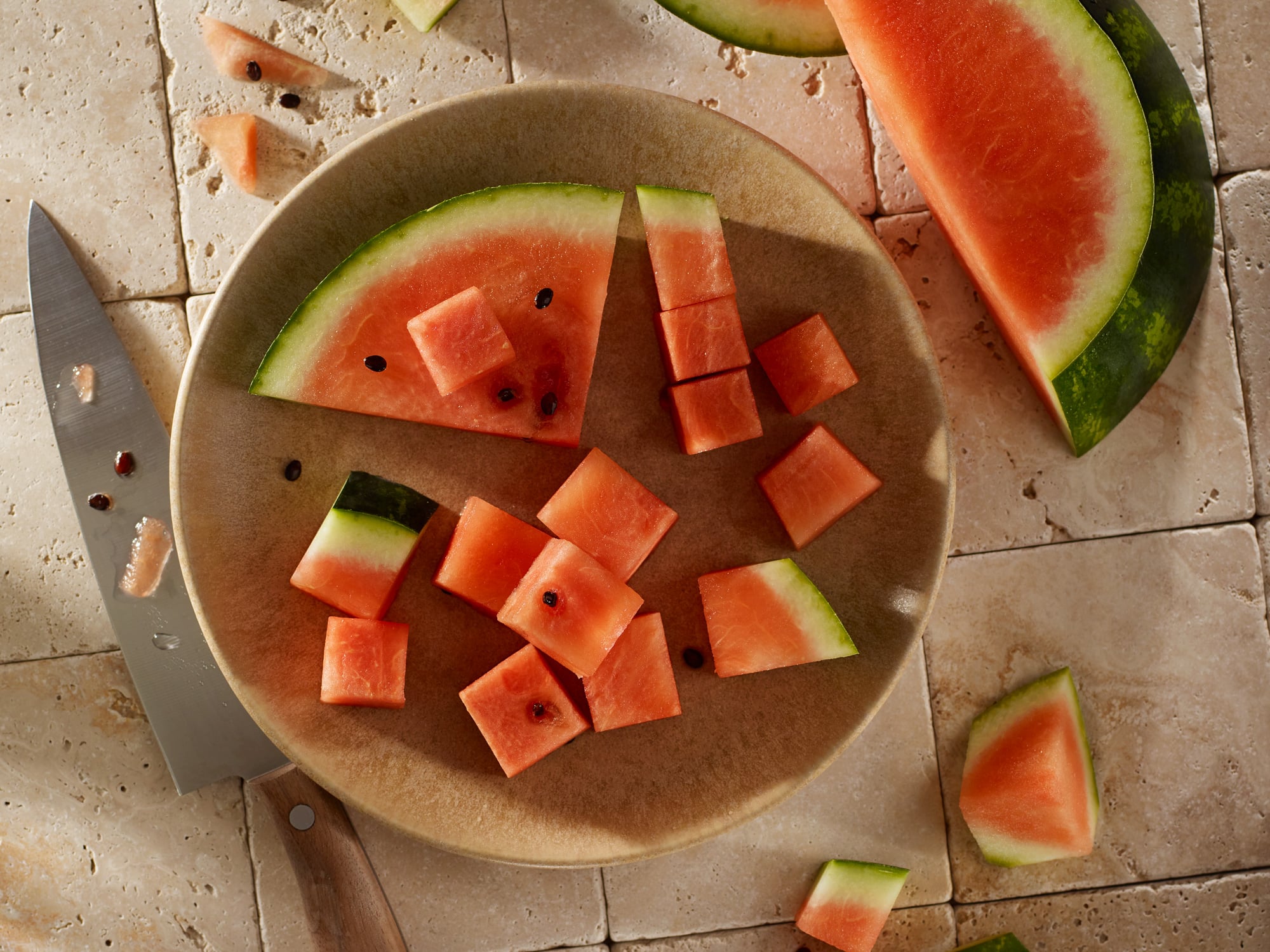 Aufgeschnittene Wassermelone auf Steinfliesen von oben fotografiert.
