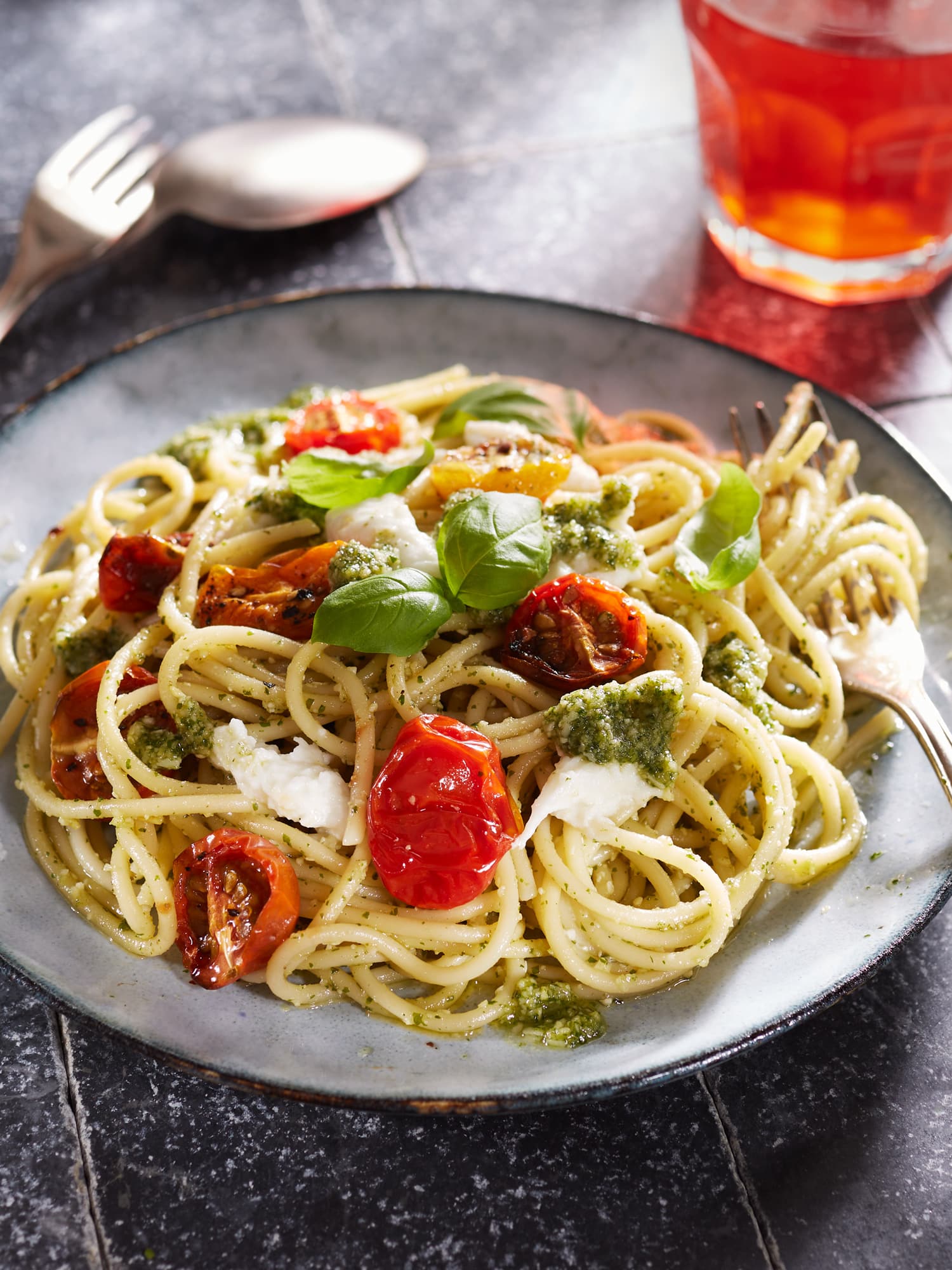 Spaghetti mit Pesto und Tomaten, dazu Mozzarella und frisches Basilikum.