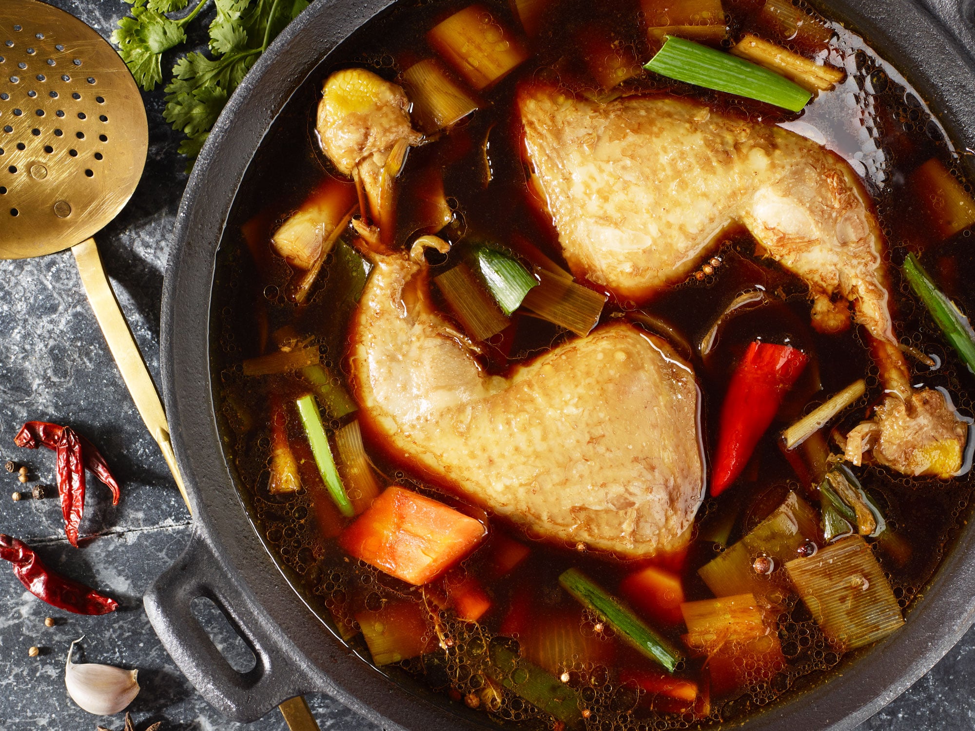 Asiatische Hühnerbrühe mit Hähnchenoberkeulen, Suppengemüse und frischem Koriander.
