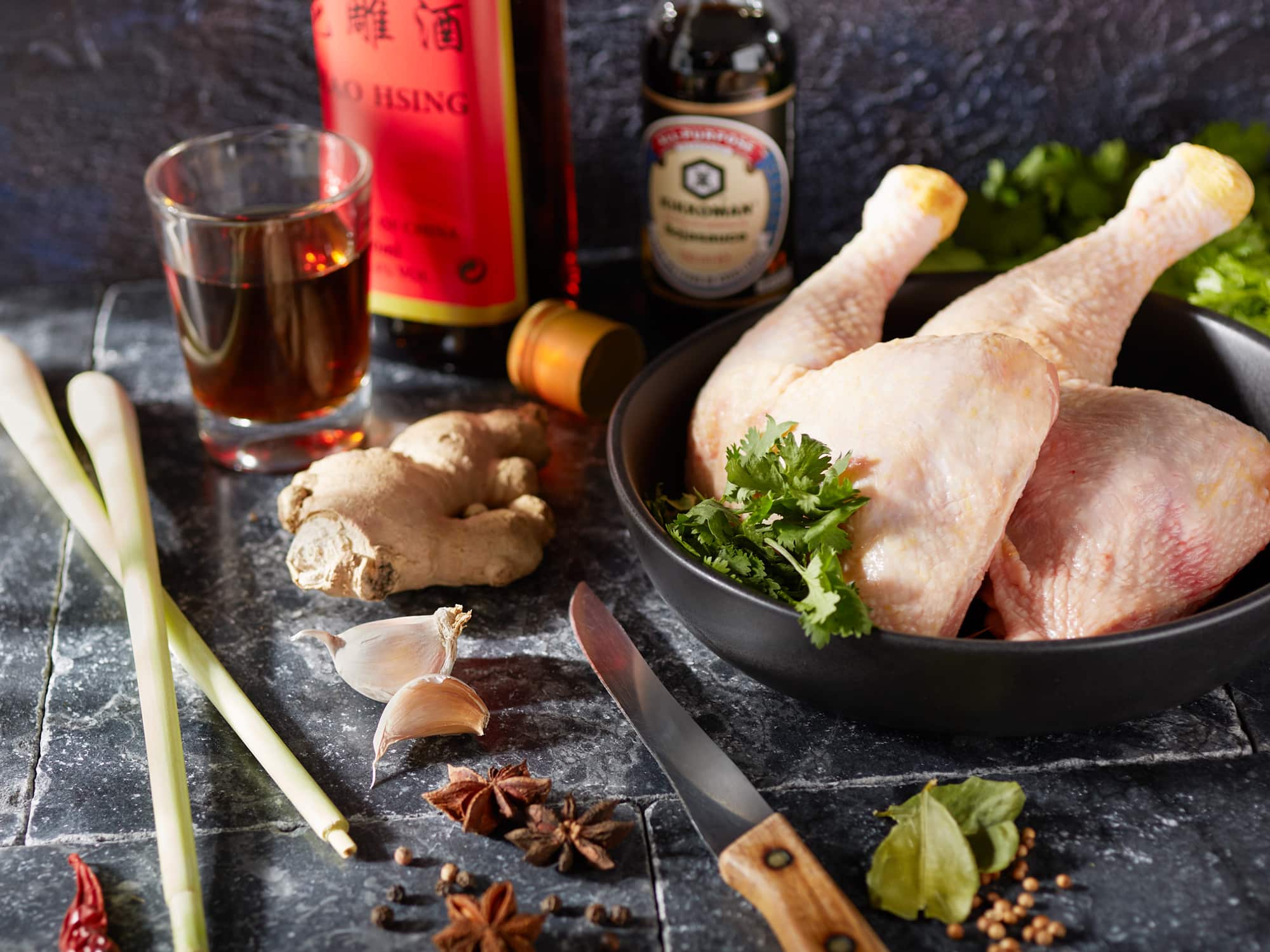 Zutaten für asiatische Hühnerbrühe mit Hähnchenkeulen, Zitronengras, Ingwer und Kochwein.