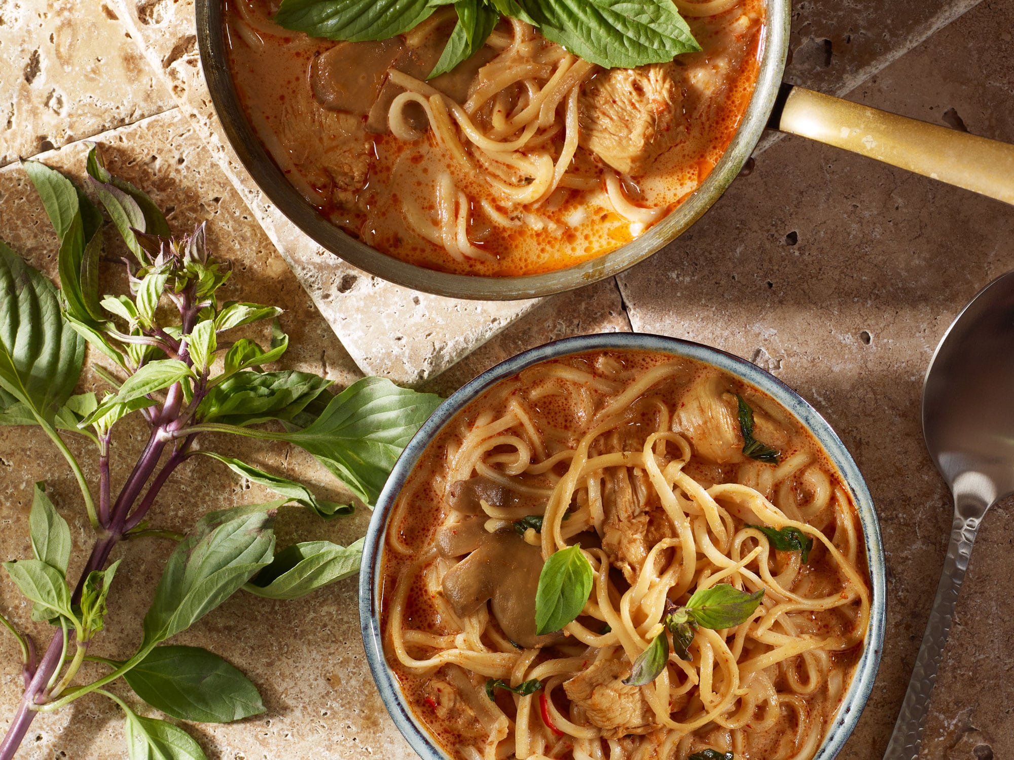 Asiatische Nudelsuppe mit frischem Thai-Basilikum, Austernpilzen, Kokosmilch und Hähnchenfleich in Vogelperspektive.