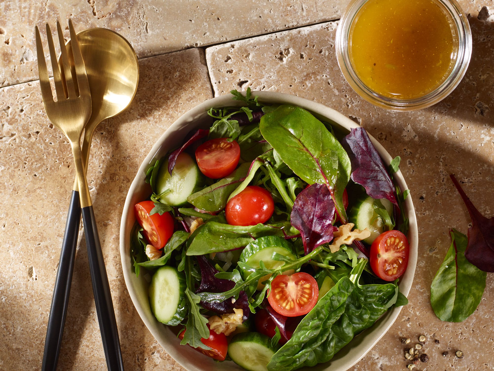 Gemischter Beilagensalat mit Honig-Senf-Dressing von oben fotografiert, auf Steinboden.