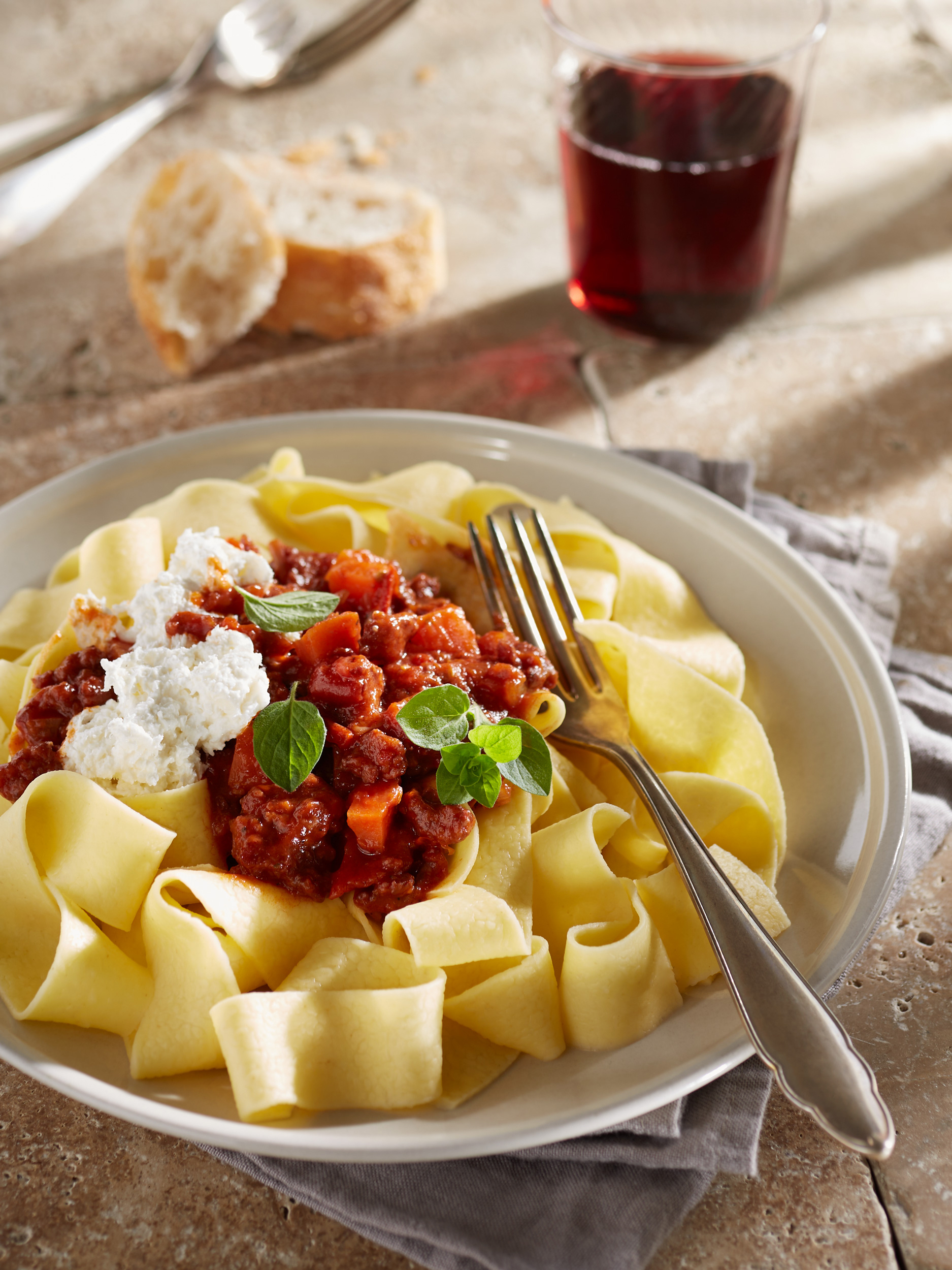 Frische Pasta mit Salsiccia Ragout, Burrata und Oregano. Dazu Baguette und ein Glas Rotwein.