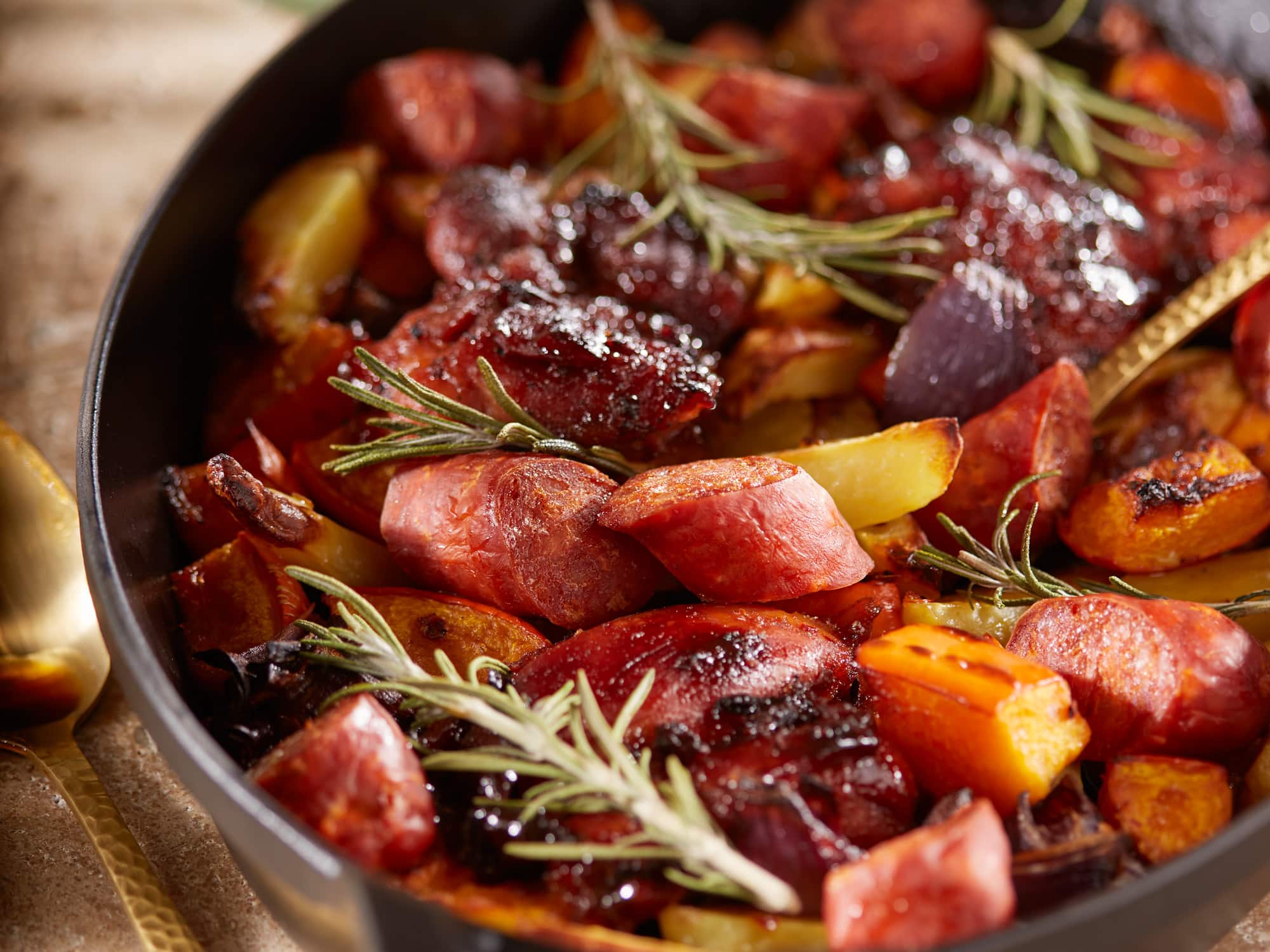 Nahaufnahme von Ofengemüse mit Kürbis, Kartoffeln, Hähnchen und Chorizo.