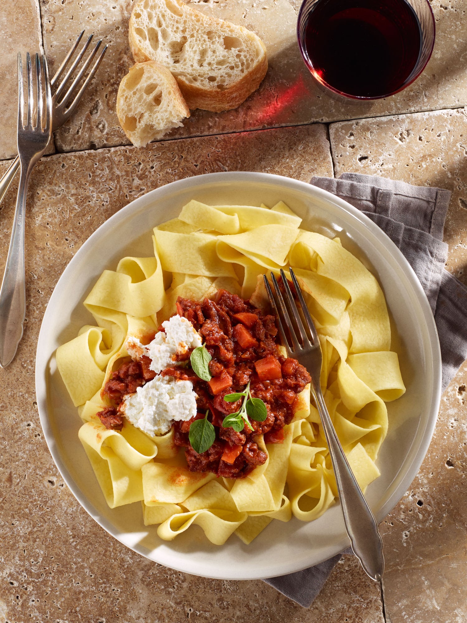 Frische Pappardelle mit Salsiccia Ragout, Burrata und frischem Oregano, dazu ein Glas Rotwein.