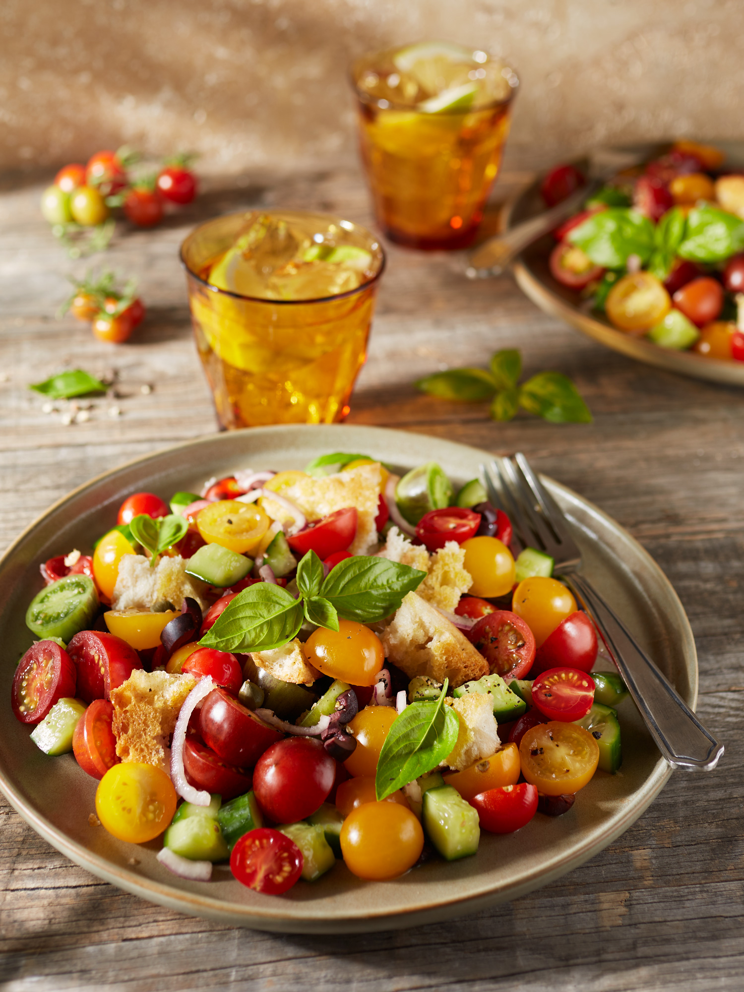 Toskanischer Panzanella Brotsalat mit bunten Tomaten, Gurken, schwarzen Oliven und frischem Basilikum.