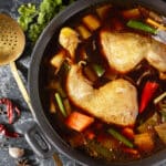 Asiatische Hühnerbrühe mit Koriander, Gemüse und Hähnchenkeulen.