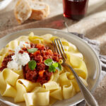 Frische Pasta mit Salsiccia Ragout, Burrata und Oregano. Dazu Baguette und ein Glas Rotwein.